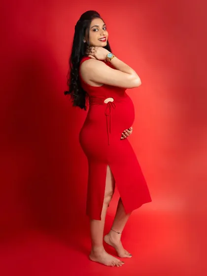 A confident side-profile pose against a vibrant red background. This shot is perfect for celebrating the beautiful curves of pregnancy.