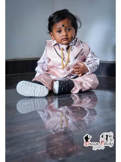 A classic seated portrait of a baby boy in a stylish outfit. The reflection on the floor provides a beautiful symmetry, and the simple background keeps the focus on him.