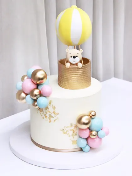 Another beautiful hot air balloon cake for a baby shower, this time with a yellow and white balloon and a sweet teddy bear peeking out of the basket.