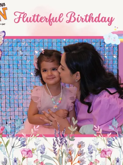A sweet moment at a butterfly and rainbow-themed birthday bash. A mother's kiss for the birthday girl captures the love and joy of the celebration.