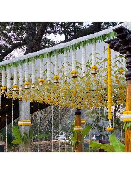 I designed this simple yet beautiful South Indian wedding decor with classic wooden pillars, fresh white chrysanthemums, and temple bells. The addition of plantain leaves adds an authentic touch to the elegant and timeless theme.