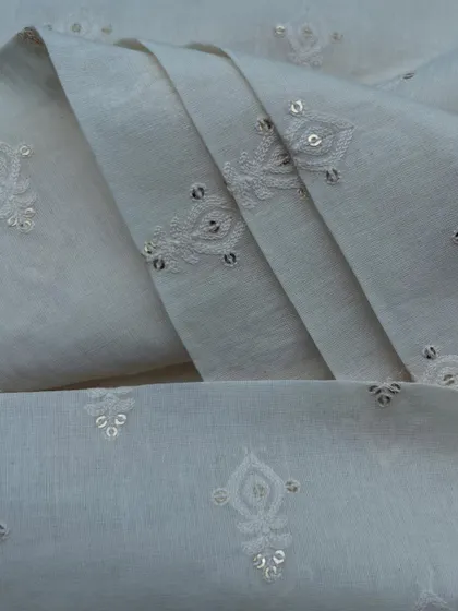 A classic white embroidered cotton with delicate buti embroidery and sequin highlights, a timeless choice for graceful ethnic wear.