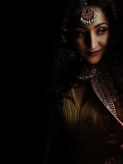 A dramatic, low-light portrait of a bride with beautiful curly hair, highlighting her features and jewelry.