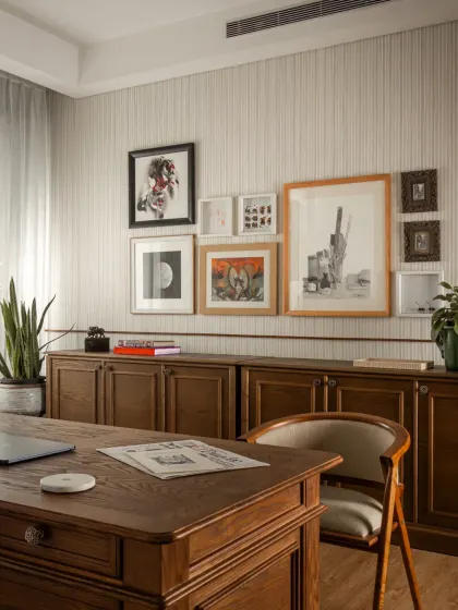 A gallery wall of personal art and photographs makes the study feel curated and lived-in. The credenza provides ample storage, keeping the desktop clear.