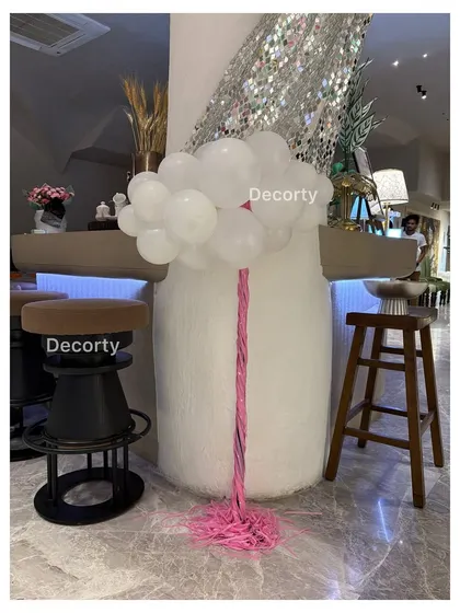 A simple white balloon arrangement with a pink tassel, adding a touch of elegance to the party decor.