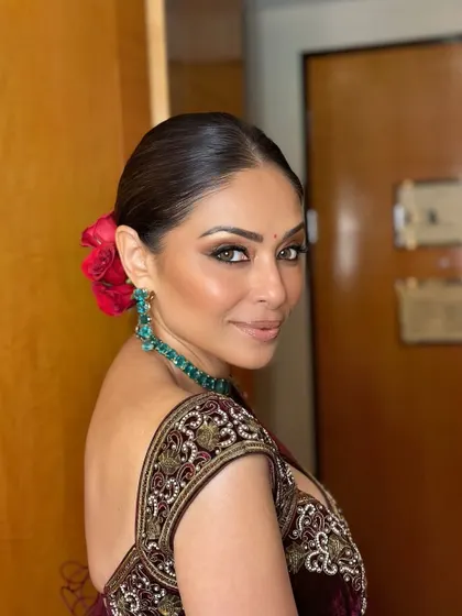 Another angle of this sculpted party glam. The addition of red roses in her hair adds a classic touch that contrasts beautifully with the modern, smokey makeup.