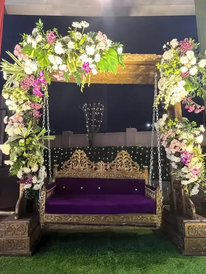 A beautifully decorated swing for the bride at a Mehendi ceremony. The royal purple seat is framed with lush floral arrangements, creating a perfect spot for photos and rituals.