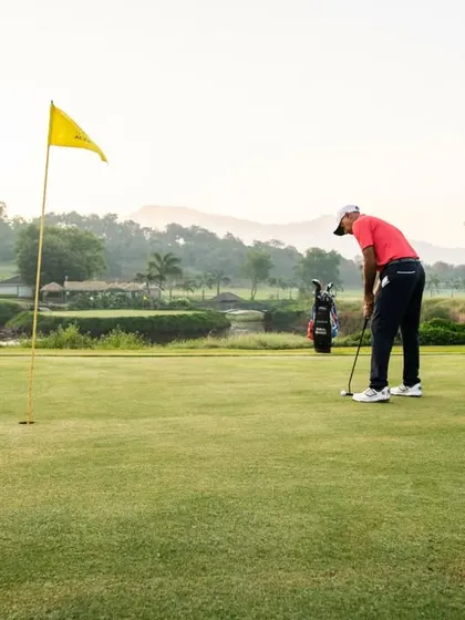 A player lines up a crucial putt on the green. This photo captures the focus and precision required for the short game, with the signature '9 Aces' flag in the hole.