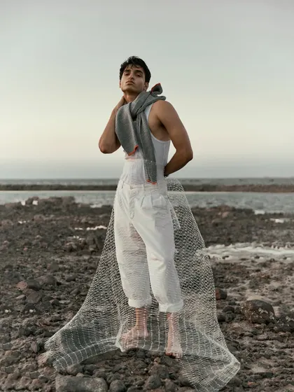 A full-length shot that showcases the dramatic landscape and the styling. The net trailing behind the model creates a beautiful, ethereal silhouette.