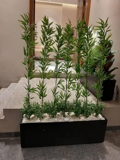 A simple yet effective divider made from artificial bamboo stalks in a long black planter, placed at the top of a set of stairs.