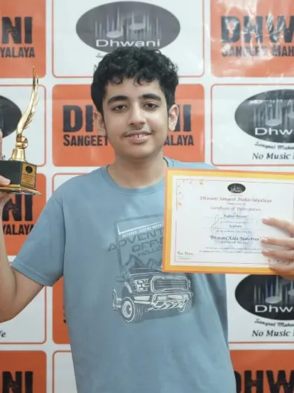 A young man proudly holds his certificate and trophy.