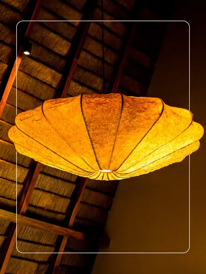 The unique, shell-shaped light fixture hanging from a thatched roof ceiling. This is an example of the small, artistic details we've added to make each space feel special.