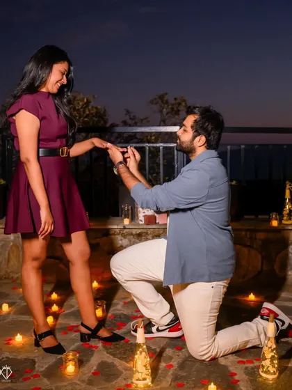 He slips the ring on her finger in a beautifully arranged proposal setting, surrounded by the warm glow of countless candles.