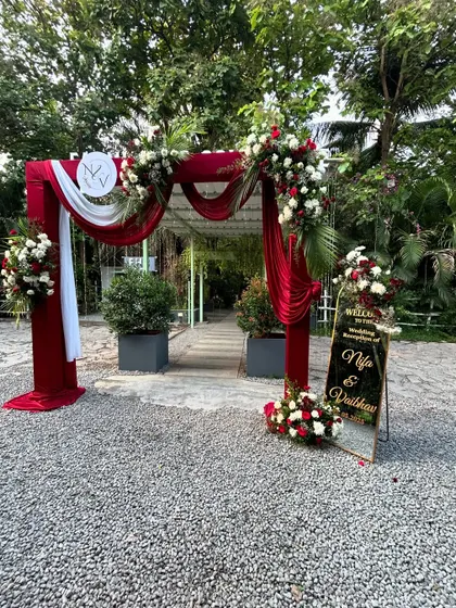 The grand entrance arch for a classic red and white themed wedding reception. The rich velvet drapes and abundant florals make a bold and elegant statement.