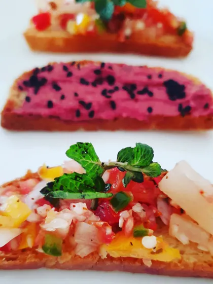 An assortment of gluten-free crostini. Toppings include a vibrant beetroot hummus and a sweet and tangy pineapple salsa.