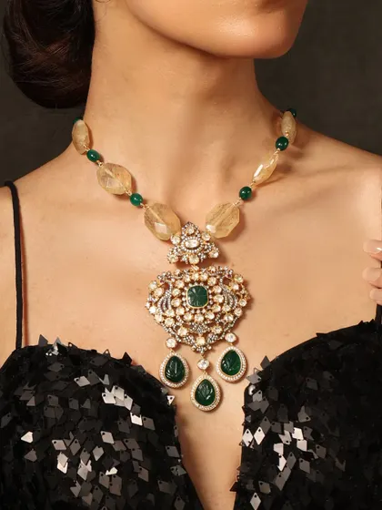 A statement pendant necklace with a large emerald centerpiece, strung on beads of yellow semi-precious stones.