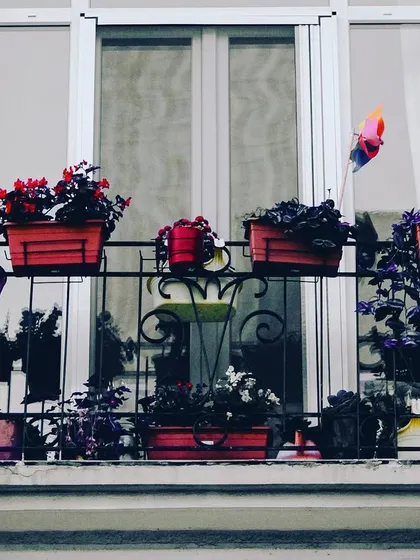 A classic European-style window balcony. We use railing planters filled with colorful flowers to add charm and curb appeal to your home's exterior.