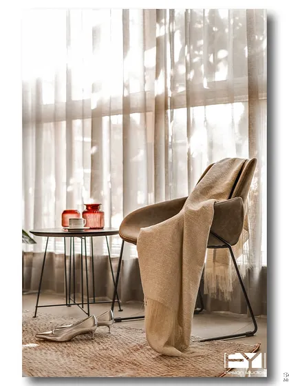 A quiet reading corner bathed in soft, diffused light from a large window. A comfortable chair, a warm throw, and a small side table create an intimate and peaceful spot for relaxation.