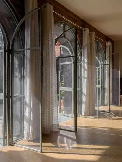 A series of custom-fabricated, slender steel-framed arched doors at the Ferns Cottage. This element combines classic form with modern construction, allowing for light, transparency, and an elegant transition to the outdoors.