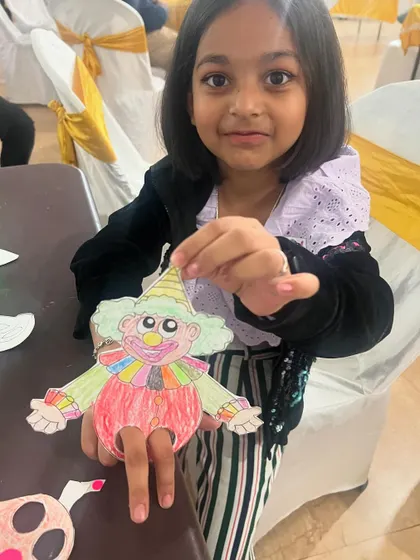 A young artist proudly displays the clown finger puppet she created. Our craft activities are designed to be fun for a wide range of ages.