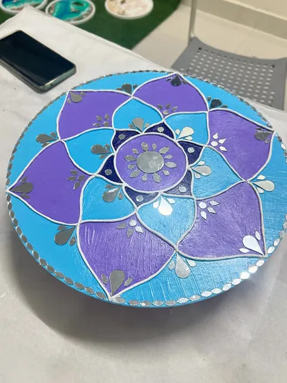 A lovely mirror art piece with a floral or lotus pattern in shades of purple and blue.