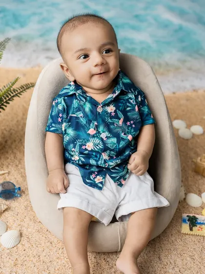 A sweet, content expression. Even without the sunglasses, his charm shines through in this tropical-themed baby photoshoot.