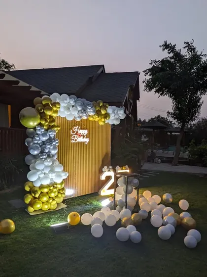 An angled view of the outdoor setup, showing the arrangement of the balloon arch and scattered balloons on the lawn.