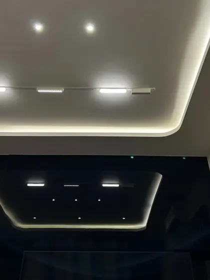 A black magnetic track light system is used here in conjunction with cove lighting, creating a layered and modern lighting scheme.