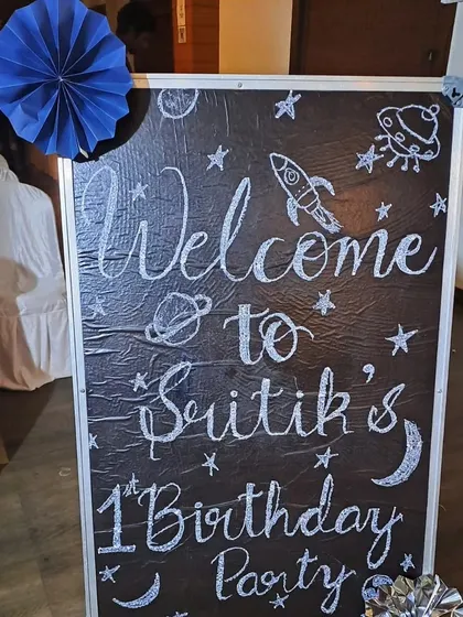 A custom welcome board for Srithik's space-themed first birthday party, hand-drawn to match the cosmic decor.