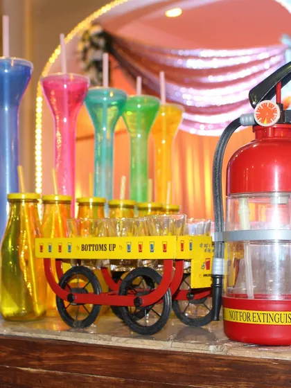 No party is complete without some fun. Here we have a selection of quirky drinkware, including colorful yard glasses, a fire extinguisher dispenser, and a miniature cart for serving shots, all designed to get the party started.