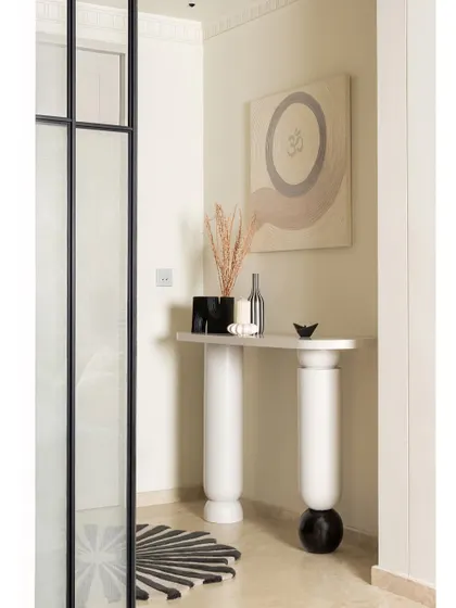 The journey into KAIA begins in this minimal yet intentional foyer. A bespoke console stands against the wall, adorned with a spiritual ‘OM’ art piece we co-designed with an artist. The space is grounded by a custom rug with a scalloped circumference, echoing the home's curved elements.
