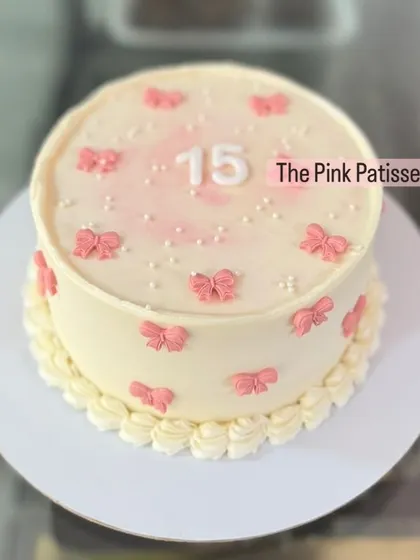 A sweet and simple cake for a 15th birthday, decorated with small pink bows and pearls.