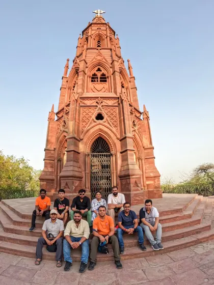 Our group poses for a photo at the Mutiny Memorial on our Northern Ridge Walk. This tour is a deep dive into the history of the 1857 uprising, set against a backdrop of lush forest.