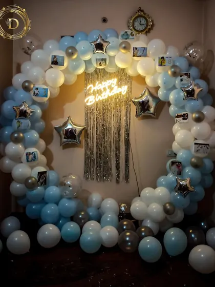 A classic color combination for a first birthday celebration. This circular balloon arch in shades of blue and white is accented with a silver shimmer curtain, star balloons, and personal photos clipped onto the frame.