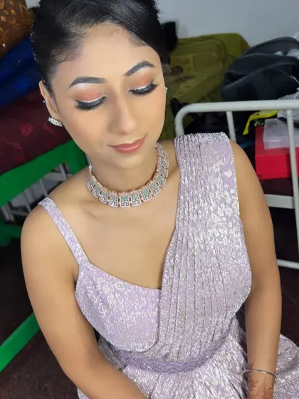 A soft and magical look for a sangeeth or reception. The makeup features a peachy-orange eyeshadow with a sharp wing and a nude lip, complementing the lavender outfit.