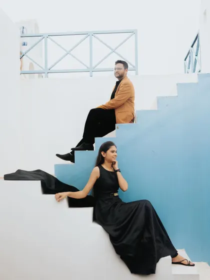 A modern and stylish pose on a staircase with a vibrant blue wall. The composition creates strong lines and a contemporary feel.