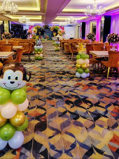 For a large venue, I place themed decorations throughout the space. Here, monkey-shaped balloon pillars are used as centerpieces for a jungle-themed Mundan party.
