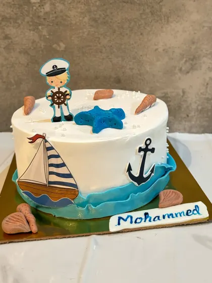 Set sail for a fun birthday with this nautical themed cake. It's decorated with a little sailor, a sailboat, an anchor, and seashells for a perfect seaside adventure.