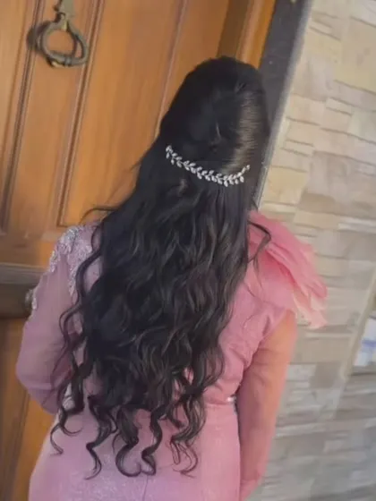 A half-up style with natural-looking waves, held in place by a simple, elegant leaf-patterned clip.