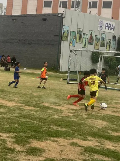 A player dribbling towards the goal in a match. Friendly matches are key to skill refinement and building confidence.