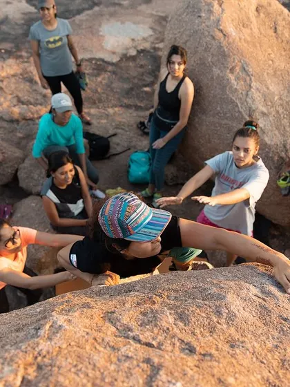 A top-down view of our crew spotting a climber as she reaches the top of a boulder. We're all in it together, celebrating every success.