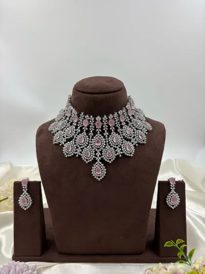 A heavy, silver-plated AD necklace set with a peacock-inspired feather design. This statement piece is available in blue, green, pink, and all-white.