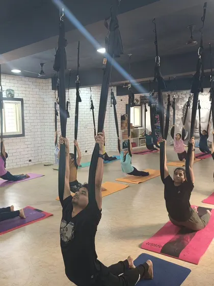 A group of students using the hammocks for a supported backbend, opening the chest and shoulders together.
