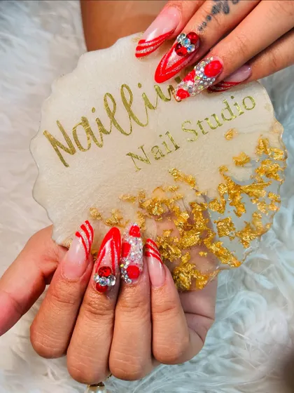 Karwachauth nails that are all about the drama. This set has it all: long stiletto shape, bold red color, glitter, and tons of 3D gems and hearts for a truly festive look.