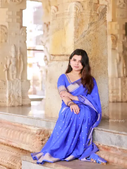 Portraits of a model in a vibrant blue saree, shot within the historic and atmospheric corridors of a temple. The stone pillars and natural light create a dramatic and timeless setting.