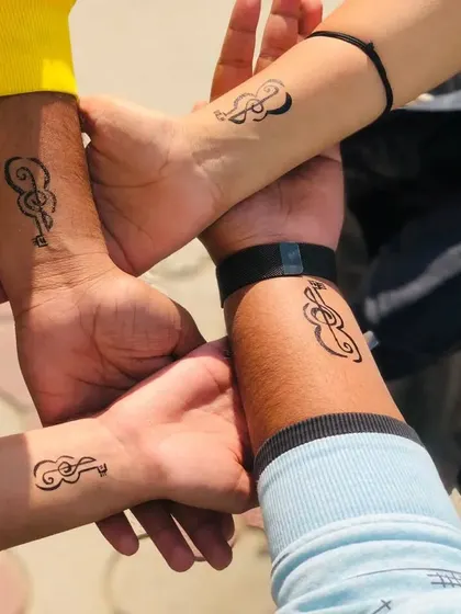 A group of friends with matching treble clef and guitar temporary tattoos on their wrists. Perfect for music lovers.