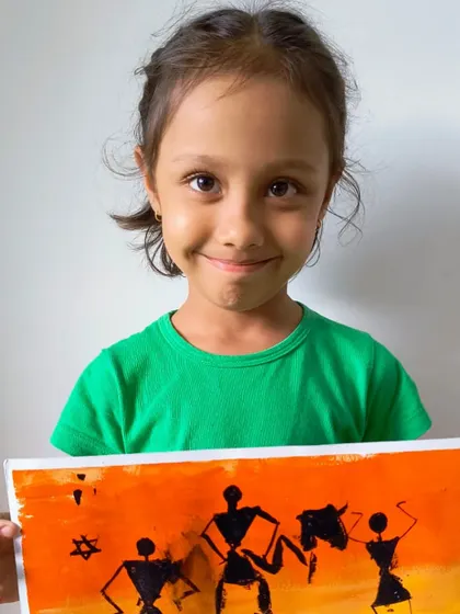 A student displays her wonderful Warli art painting, a traditional Indian folk art style we explore in our classes.