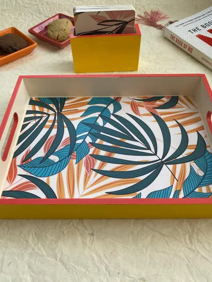A simple and elegant tray and coaster set with a tropical leaf print. The bright yellow and pink border adds a cheerful pop of color.