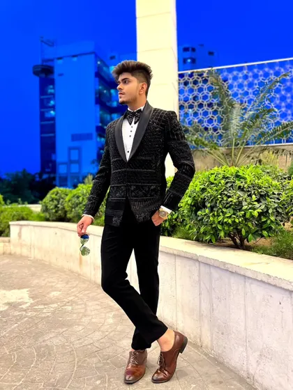 A client looking sharp in a black tuxedo with intricate beadwork. This is a perfect look for a young groom or groomsman wanting a modern, stylish outfit.