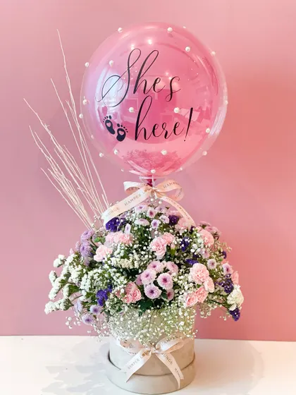 A simple and elegant way to say "She's here!". This beautiful floral hamper features a stunning arrangement of pink and purple flowers in a hat box, topped with a personalized pink balloon.